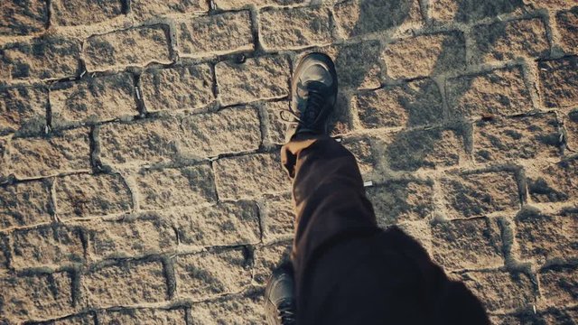 Top view POV of man in shoes walking at historical ancient sidewalk