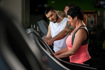 Personal coach talking with female client in gym