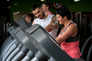 Fototapeta na wymiar Fitness coach assisting his client on treadmill