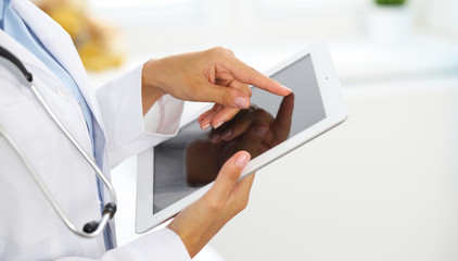 Woman doctor using tablet computer while standing straight in hospital