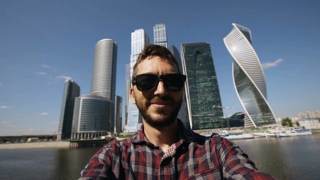 Happy tourist man taking selfie picture using smartphone near international business center in Moscow