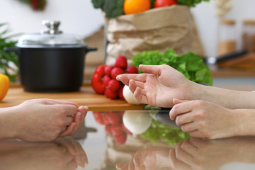 Close-up of human hands are gesticulate over a table in the kitchen. Women choosing menu or making online shopping. So much ideas for tasty cooking