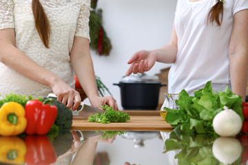 Close-up of  human hands  cooking in a kitchen. Friends having fun while preparing fresh salad. Vegetarian, healthy meal and friendship concept