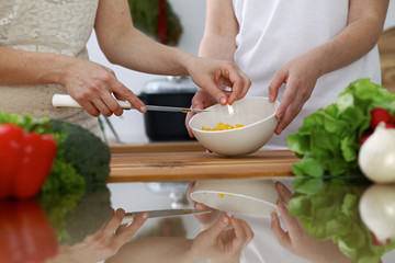 Close-up of  human hands  cooking in a kitchen. Friends having fun while preparing fresh salad. Vegetarian, healthy meal and friendship concept