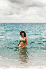 Fototapeta na wymiar Beautiful woman portrait bathing in the sea and looking at camera