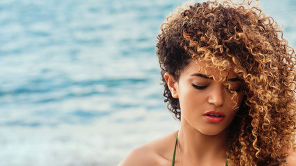 Beautiful woman portrait on the beach, looking down