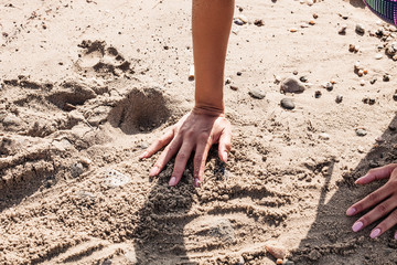 Female hands playing with the sand on the beach