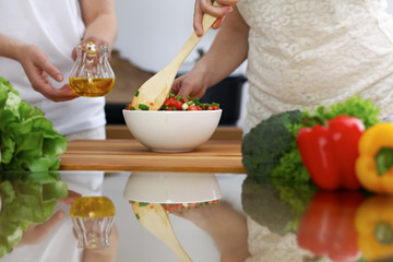 Close-up of  human hands  cooking in a kitchen. Friends having fun while preparing fresh salad. Vegetarian, healthy meal and friendship concept