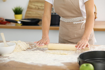 Female hands making dough for pizza or bread while using rolling pin. Baking concept