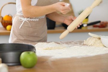 Female hands making dough for pizza or bread while using rolling pin. Baking concept
