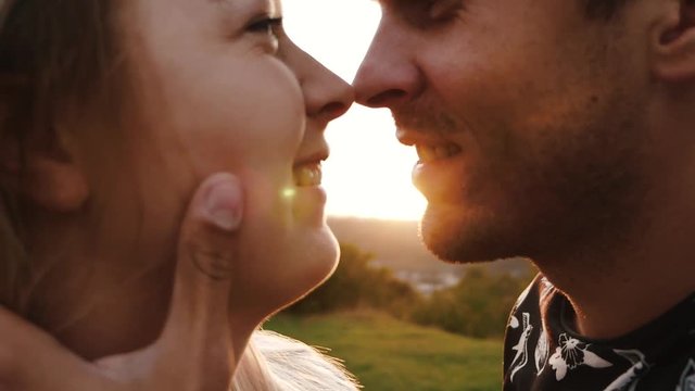 Loving couple rubs their noses at sunset