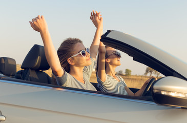 Two attractive young women in a cabriolet car