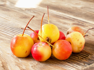 Small paradise apples on wooden table with sun rays in warm autumn day