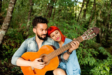 Young couple having fun with guitar in the park.