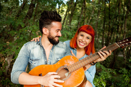 Young couple having fun with guitar in the park.
