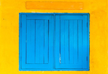 Obraz na płótnie Canvas Blue window on the yellow wall.