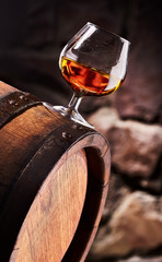 Glass of cognac on the old wooden barrel