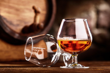 Two glass of Cognac and old oak barrel defocussed