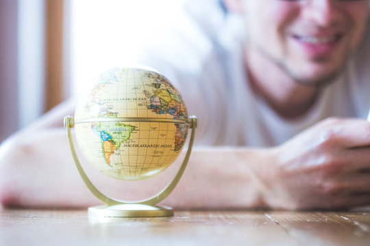 Junger Mann plant Weltreise, Globus und Landkarte