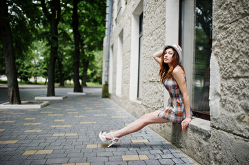 Fototapeta na wymiar Amazing long legs with hig heels girl wear on hat sitting on the window sill on streets of city.