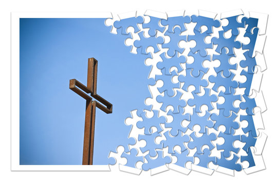 Rusty iron cross against a blue background - Rebuild our faith - Christian cross concept image in jigsaw puzzle shape.