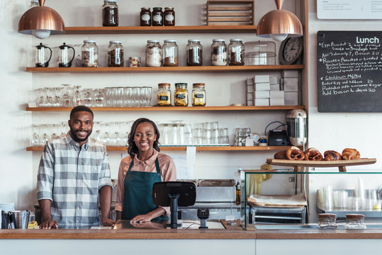 Two smiling young African entrepreneurs standing at their bakery counter