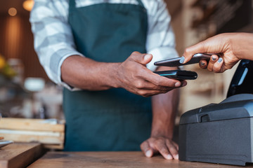 Customer using her smartphone to pay for her cafe purchase