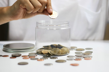 Woman's hand putting coins in jar. Concept of money saving and financial. Selective focus.
