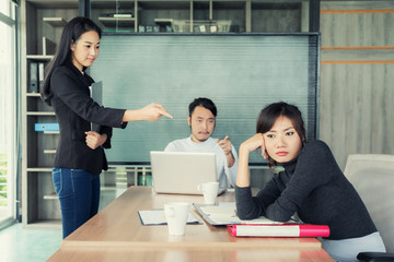 Group of Asian business people looking at businesswoman and blaming colleague for failure, bad work...