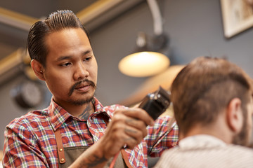 Serious thai hairdresser cutting his clients hair