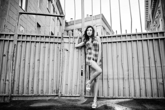 Amazing long legs with hig heels girl wear on hat against iron fence.