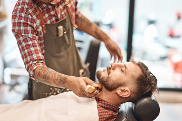Obraz na płótnie Canvas Professional barber finishing shaving his customers beard