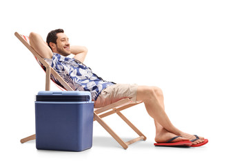 Tourist relaxing in a deck chair next to a cooling box
