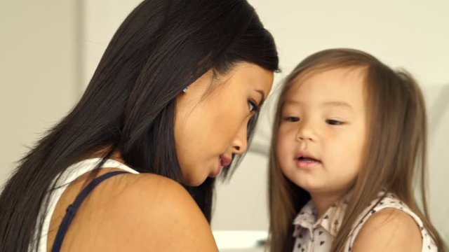 Close up side view of Happy asian mother and daughter beats on their foreheads at home