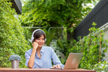 Asian women play notebooks and listen to music in the garden.