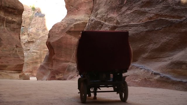 Horse-drawn carriage in Siq - narrow passage that leads to Petra, originally known to Nabataeans as Raqmu - historical and archaeological city in Hashemite Kingdom of Jordan