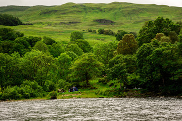 Camping tents on a slope of the hill at Loch Tay lake coastline, central Scotland