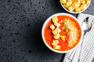 Tomato and basil soup with pasmesan and croutons on dark background. Top view, copy space. 
