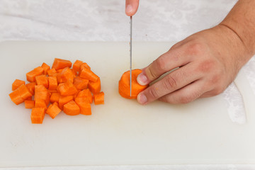 Food preparation - cutting the carrott with knife on the white board