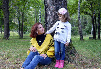 family mom and daughter reading a book in the woods