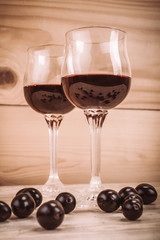 Two glasses of red wine and grapes on wooden table