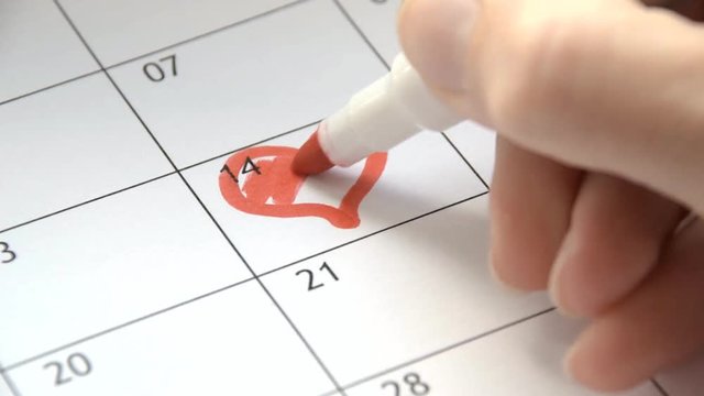 Writing RED HEART on 14th February on calendar with a red marker