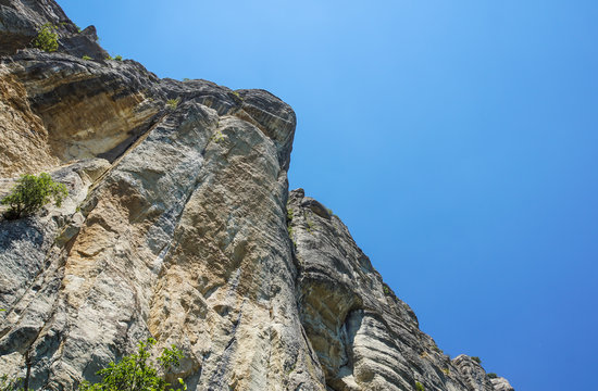 rocky wall of a mountain stretching up to the blue sky