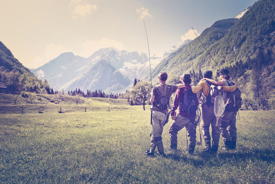 Slovenia, Bovec, four anglers standing on meadow near Soca river
