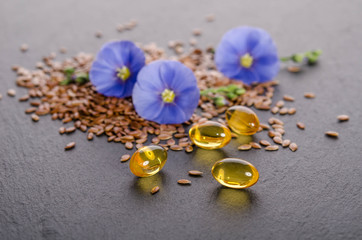Flax seeds , beauty flower and oil in caps on a grey background. Phytotherapy.
