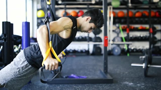 Young fit hispanic man in gym doing push ups on kettlebell.