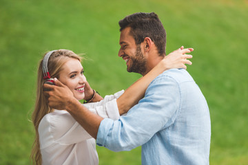 smiling woman in headphones and boyfriend