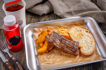 Fast food in a restaurant. A well-fried steak with golden crispy french fries and toasted crispy toast. Combo lunch.