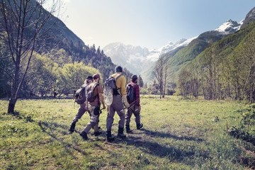 Slovenia, Bovec, four anglers walking on meadow towards Soca river