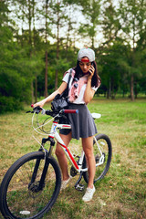 Fototapeta na wymiar Young woman using smartphone with riding bicycle in park